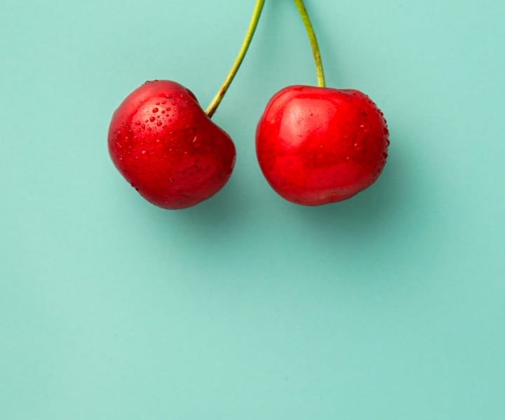 two cherries with teal background